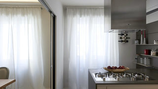 Cucina con piano cottura in acciaio e mensole a parete. Ristrutturazione Balduina Roma. (Progetto Scintille)