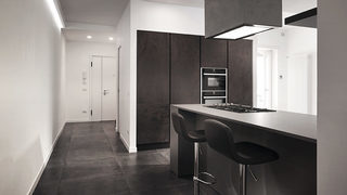 Cucina moderna con piani in materiale scuro e isola centrale. Ristrutturazione Quartiere Collatino Roma. (Progetto Ouverture)