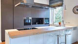 Soggiorno con divano in velluto viola, TV a parete e arredo in legno. Ristrutturazione Parioli Roma. (Progetto Poésie)